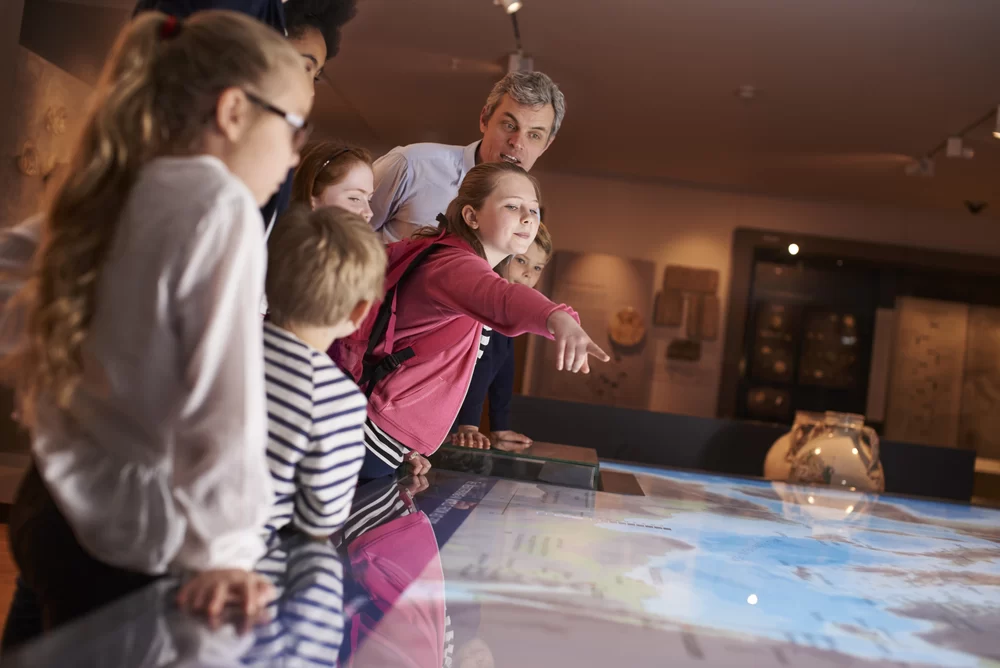 Pupils,On,School,Field,Trip,To,Museum,Looking,At,Map